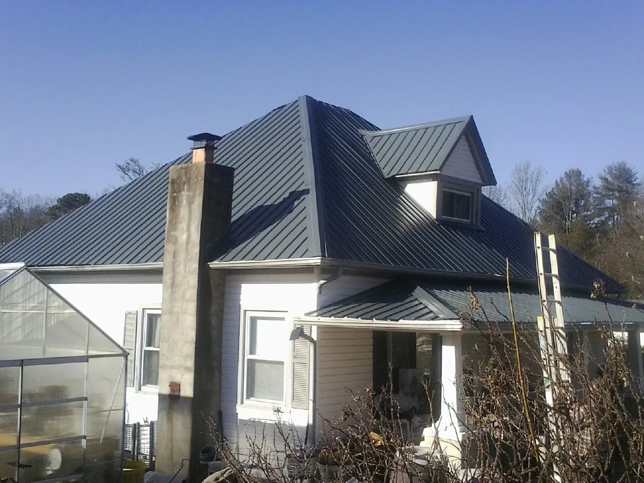 Dark blue standing seam metal roof on a white farmhouse with dormer — Slate & Tile Roof Repair by Roofing Brothers in Running Springs