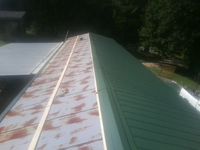 Old rusted panels beside newly installed green metal roofing — Wind Damage Roof Repair by Roofing Brothers in Running Springs