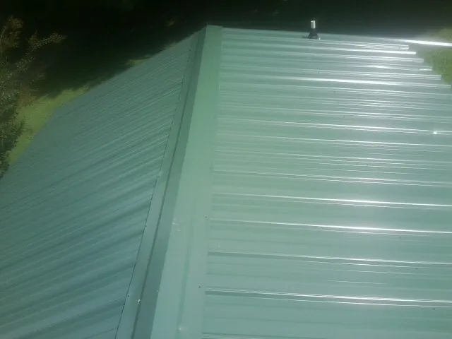 New green metal panels meeting at the ridge of a roof — Flat Roof Repair work by our crew in Running Springs