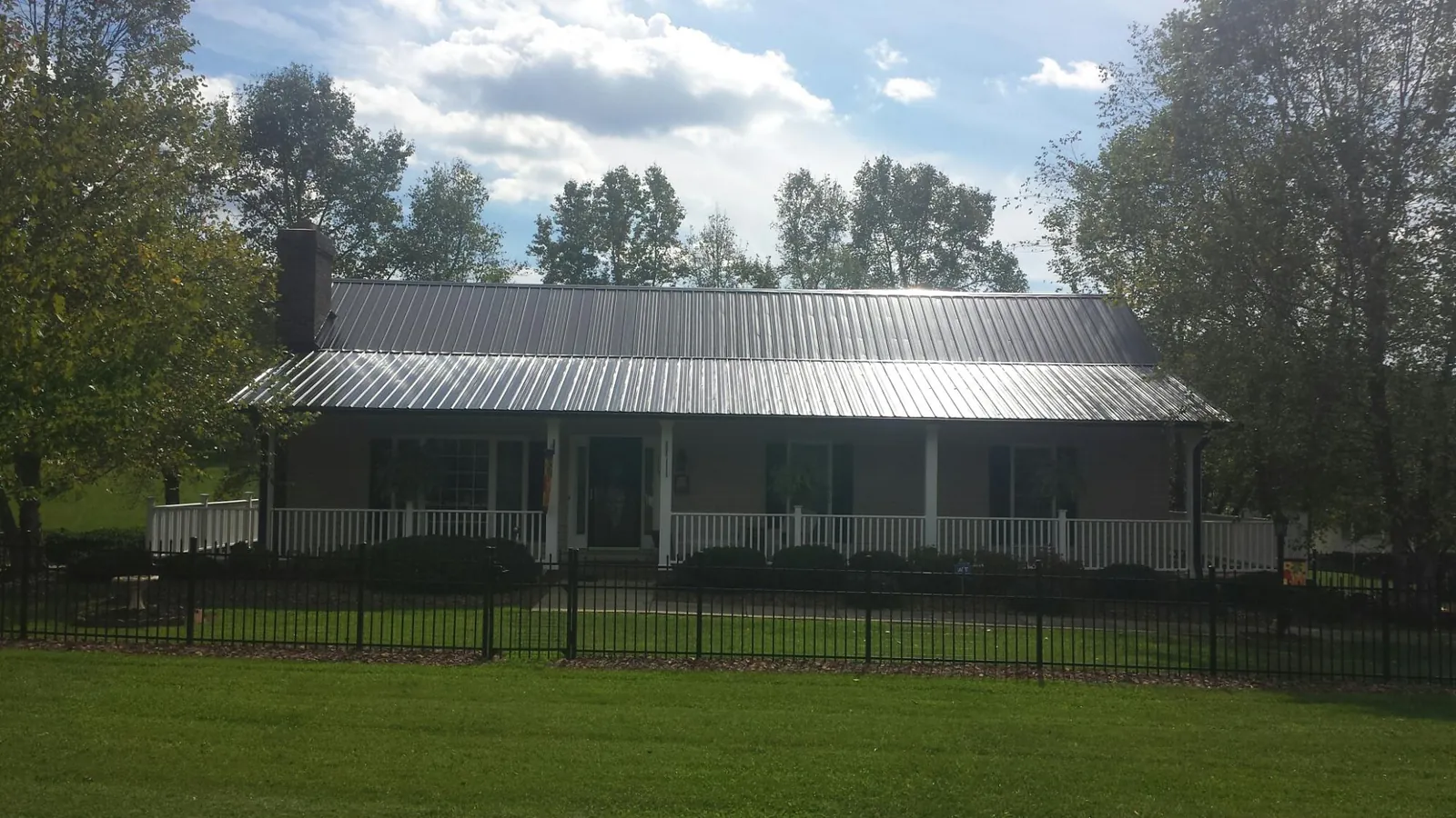 Gray metal roof on a brick ranch with a full width front porch — Gutter Guard Installation work by our crew in Running Springs