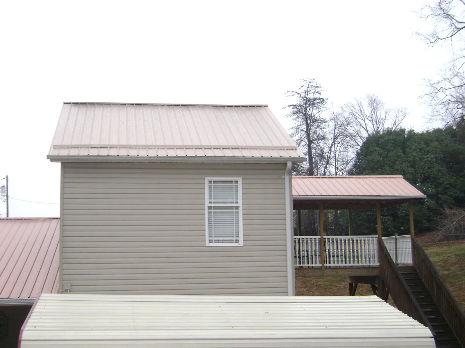 Tan metal roofs on a two story addition and attached porch, from a Roof Replacement job in Running Springs