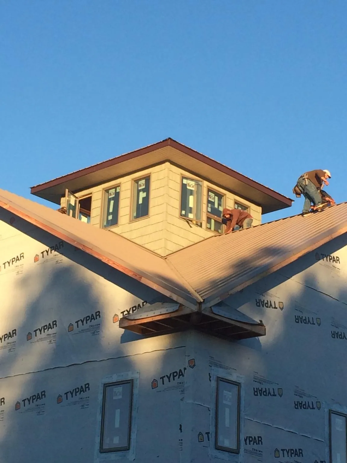Roofers working around a rooftop cupola on a new metal roof at sunset — Roof Waterproofing in Running Springs by Roofing Brothers